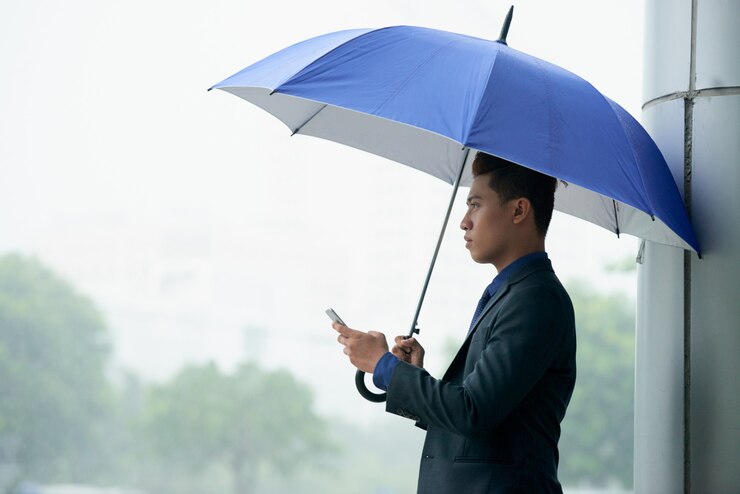 asian businessman standing street with umbrella during rain using smartphone 1098 20227